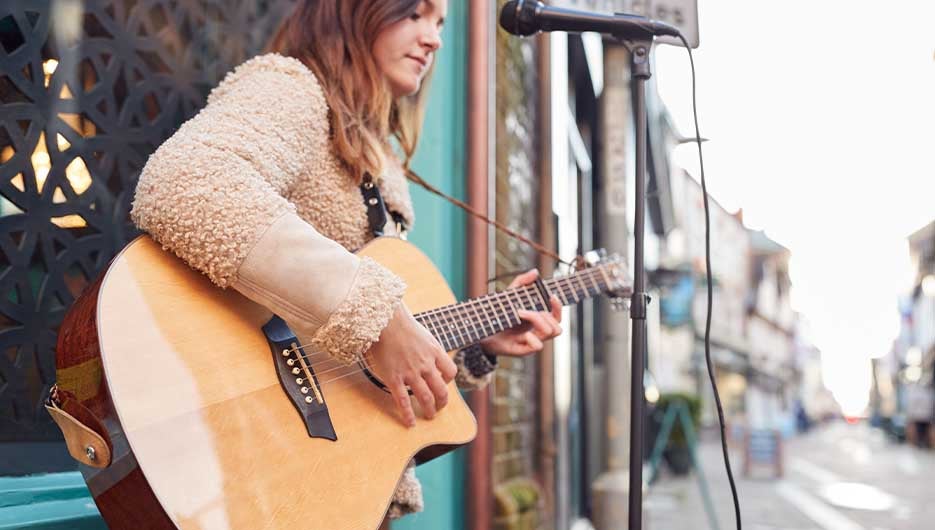 woman busker playing guitar