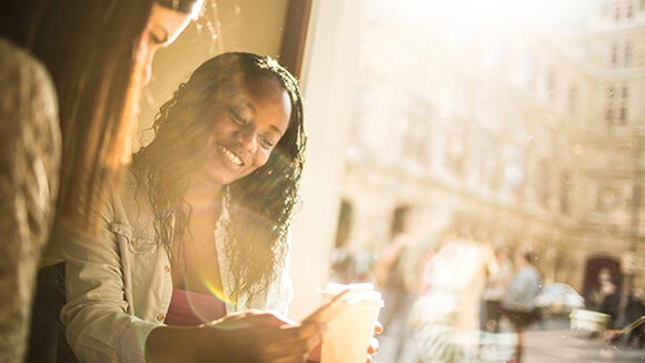 women smiling women smiling looking at cellphone