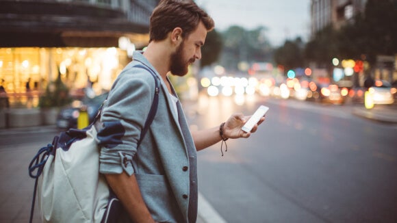 Man looking at phone before crossing the street