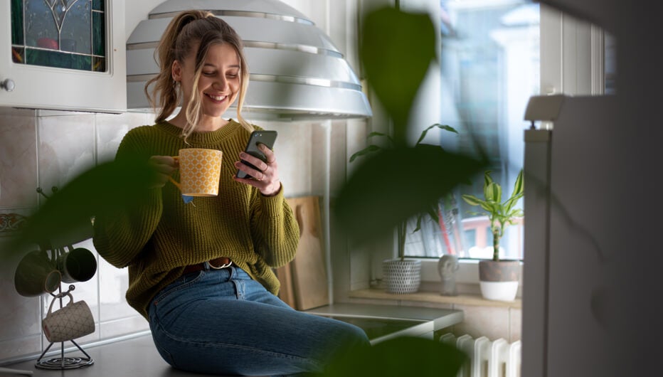 girl on phone with coffee in kitchen